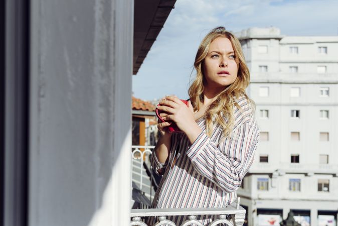 Young cheerful female with cup on terrace
