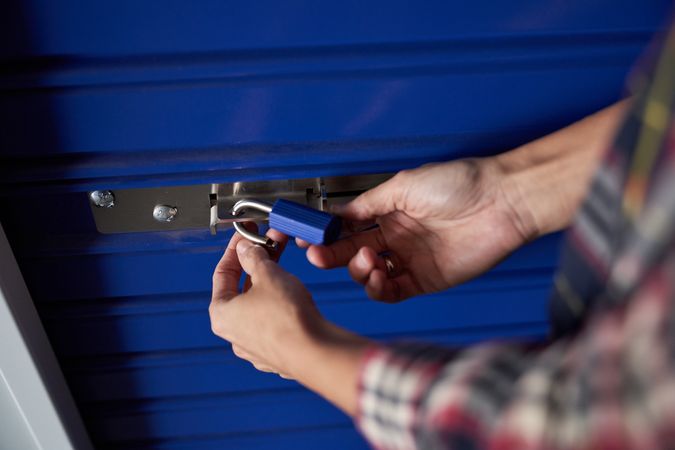 Nice woman's hands holding a blue padlock while closing it