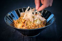 Unrecognizable person putting crisps on fried rice