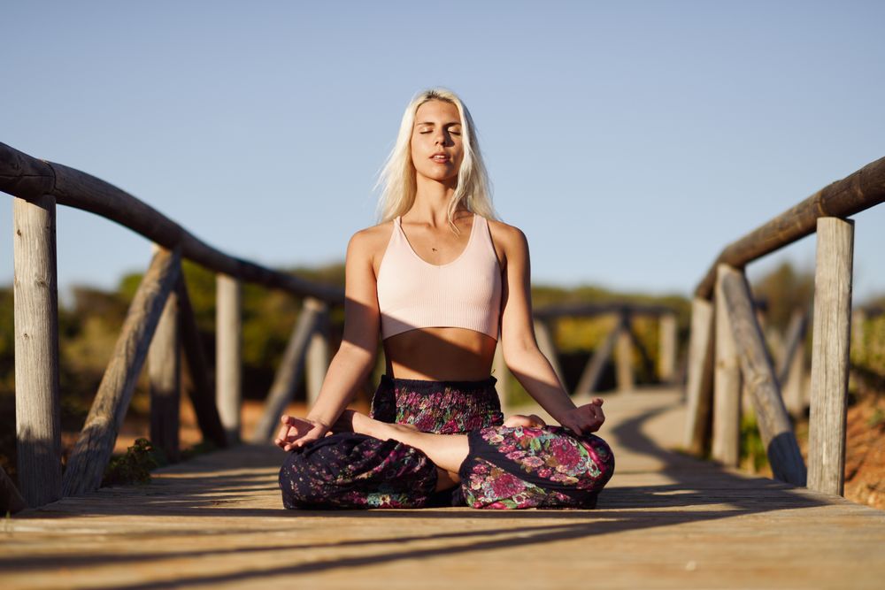 Woman practicing yoga on wooden bridge