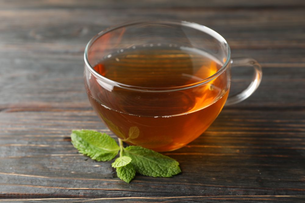 Cup of tea with mint on wooden background, close up