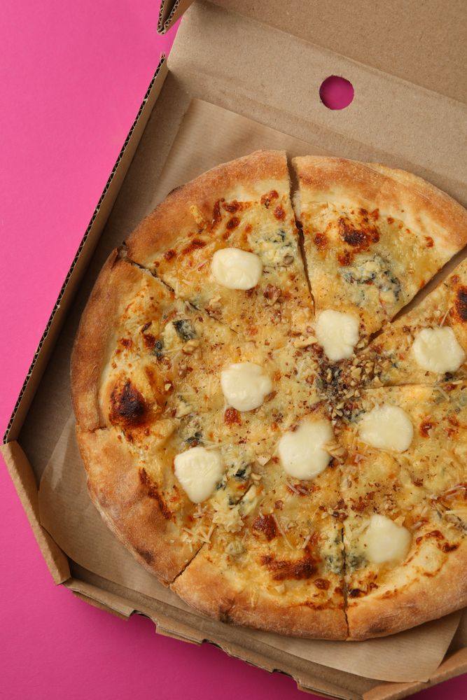 Cheese pizza in carton box on violet background