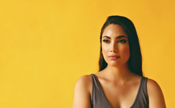 Calm Hispanic woman looking away in yellow room