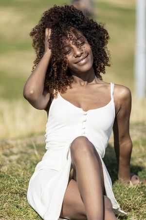 Female in light summer dress relaxing in park enjoying the sun