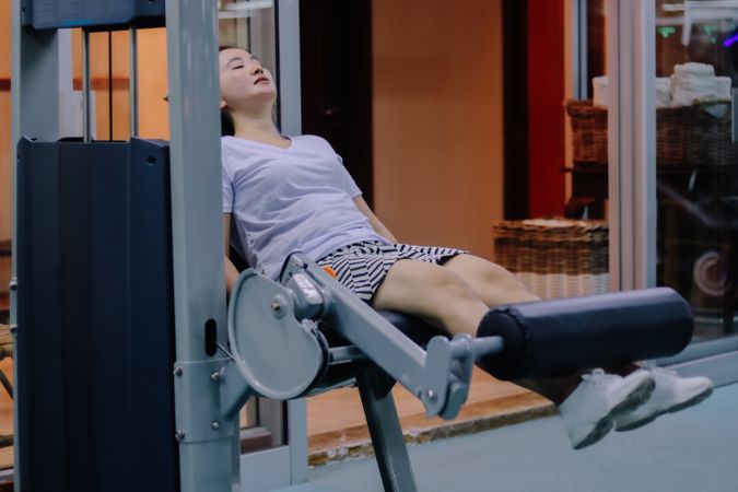 A woman in Asia uses a leg extension machine at a fitness center
