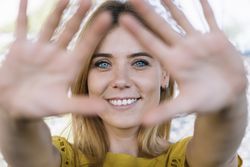 Young smiling woman pulling hands to camera
