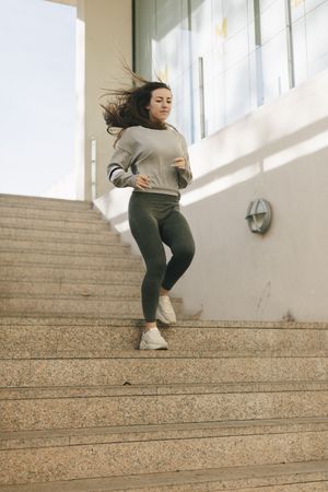 Woman running down concrete stairs outside in an urban setting