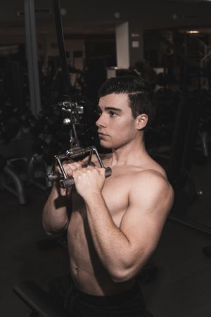 young fitness man doing machine weights in the gym