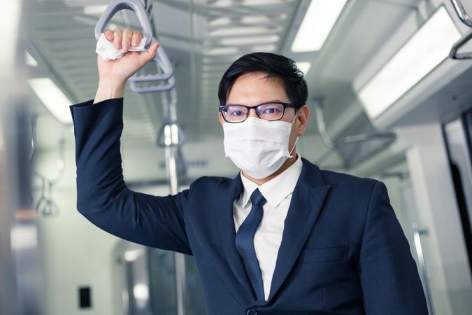 Businessman in facemask standing in metro car