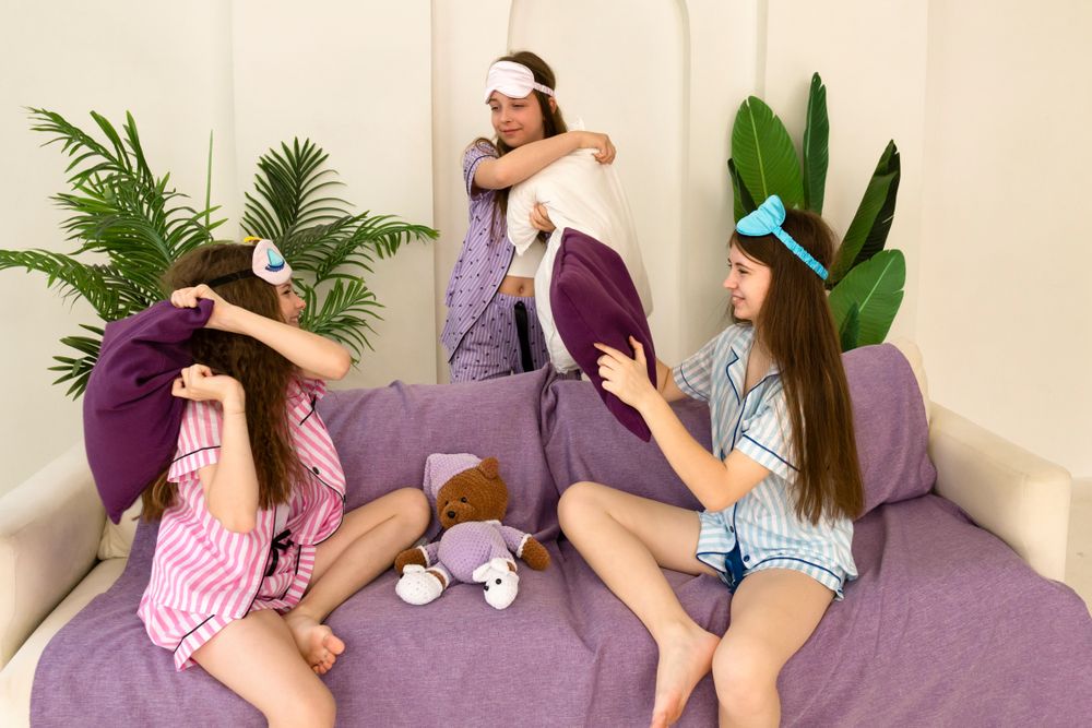 Sisters playfully hugging and laughing on the couch.