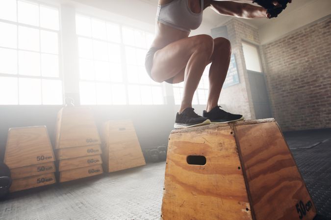 Fit young woman box jumping at a crossfit gym
