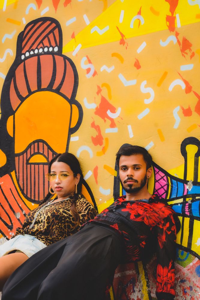 Man and woman in casual outwear leaning on graffiti wall