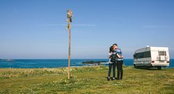 Couple kissing near the coast with a camper