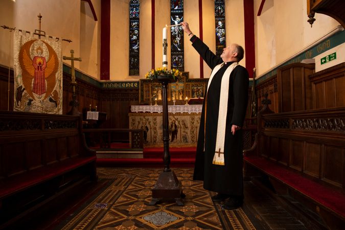 Vicar lighting candle in parish