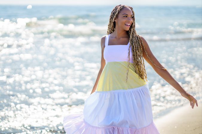 Black female walking along the shore in colorful dress