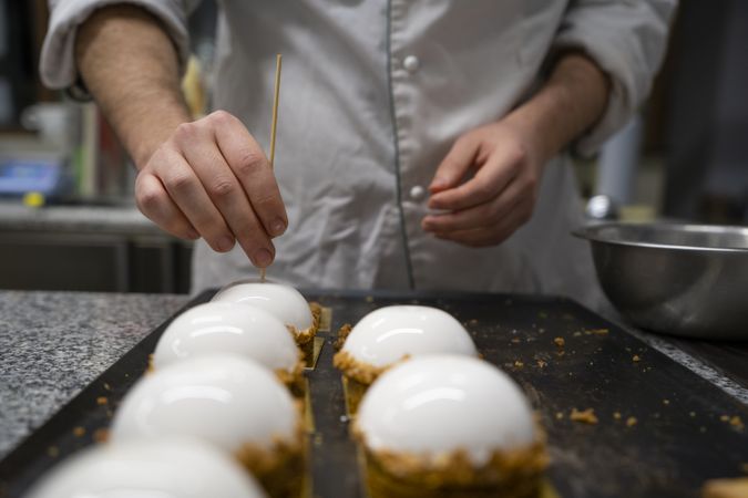 Hands putting a wooden stick into cakes