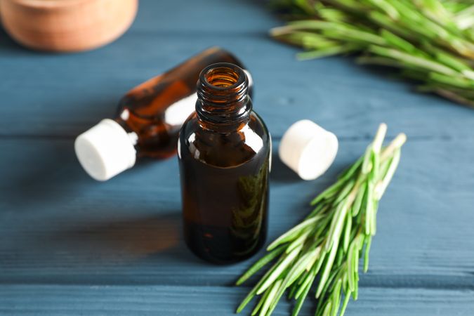 Rosemary oil and leaves on wooden background, space for text
