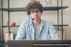 Male telemarketing talking on head set in front of laptop on desk bGRRZ2