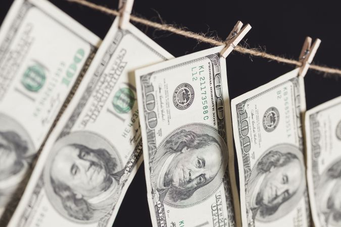 Hundred Dollar Bills Hanging From Clothesline on Dark Background