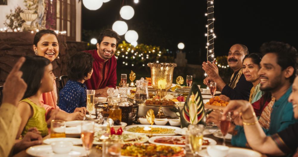 Big Indian Family Celebrating Diwali: Family Gathered Together on a Dinner Table in a Backyard Garden Full of Lights.
