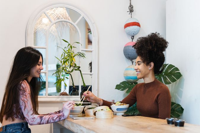 Delighted friendly multiethnic women eating in restaurant