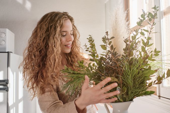 Content lady making composition of twigs at work