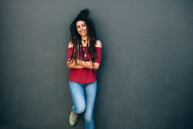 Smiling woman standing against a wall with arms crossed