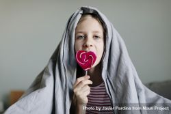 Wide view of young girl holding a pink heart shaped lollipop bYqxNb