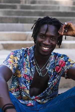 Stylish Black hipster man sitting on stairs in city