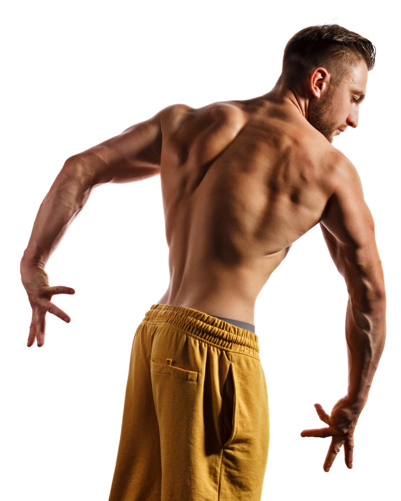 Bodybuilder practicing poses ahead of competition in light studio