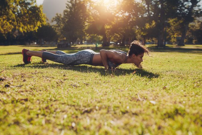 Strong woman doing push ups exercise in a park