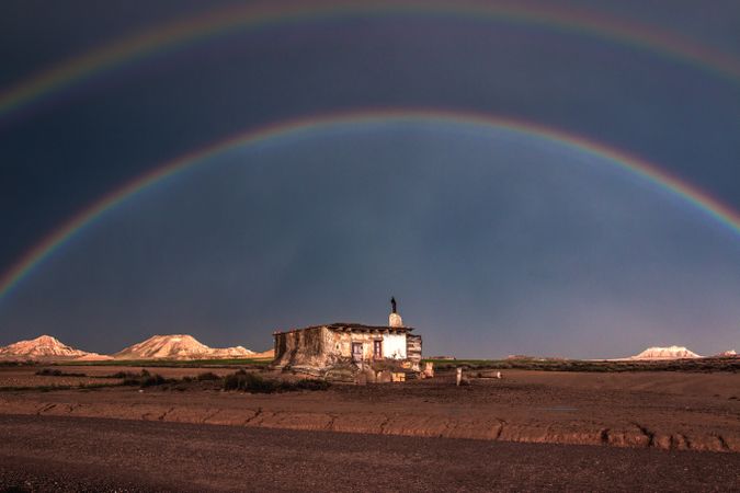 Lonely house in desert and rainbow in sky