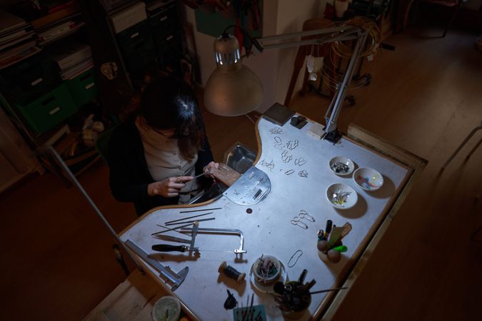 Unrecognizable female goldsmith flattening jewelry with hand fil