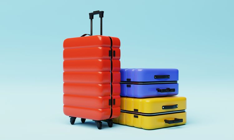 Three multi-colored hard shell roller suitcases on light yellow background