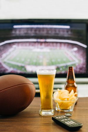 Beer and snacks prepared for watching american football on TV