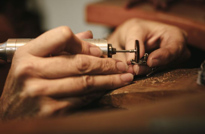 Hands of female jeweler polishing a jewelry piece with grinder machine