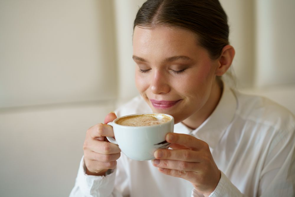 Woman smelling a delicious coffee in a cafeteria