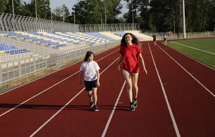 Two siblings walking on running track together