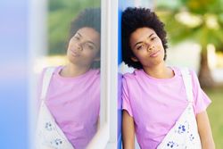 Woman looking at camera and leaning her side on blue building