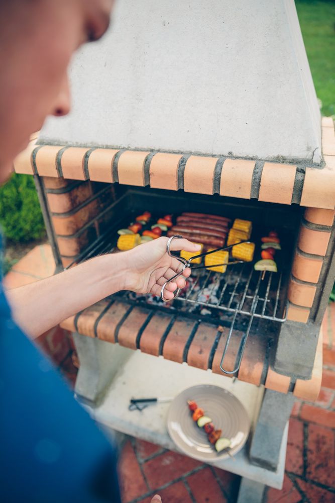 Unrecognizable young man cooking meal in barbecue