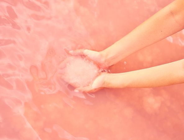 Female holding healing salt pile in pink water