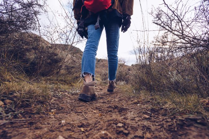 Hiker with backpack walking along pathway in autumn forest