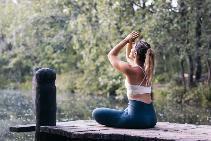 Woman meditating in nature near a lake