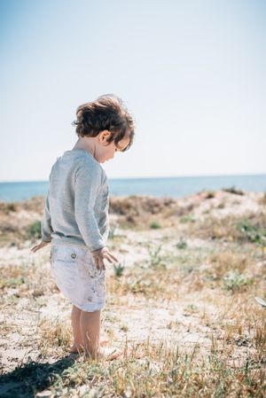 Barefoot child in short barefoot on sandy beach