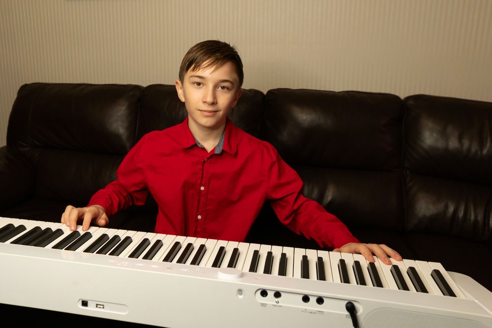 Boy in red shirt playing white keyboard