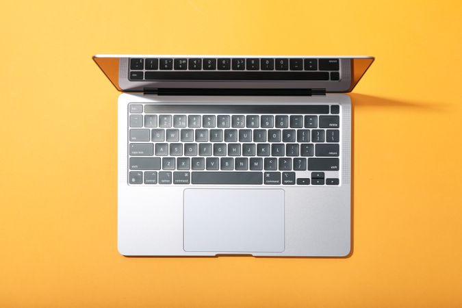 Top view of opened laptop on light orange desk