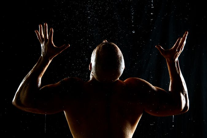 Anonymous muscular male under rain