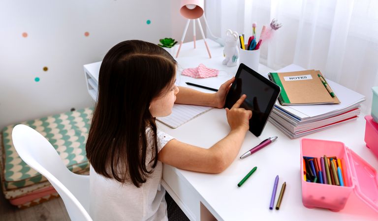 Girl studying at home with tablet and mask on table