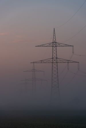 Electrical grid towers in a row on a foggy morning in a german village