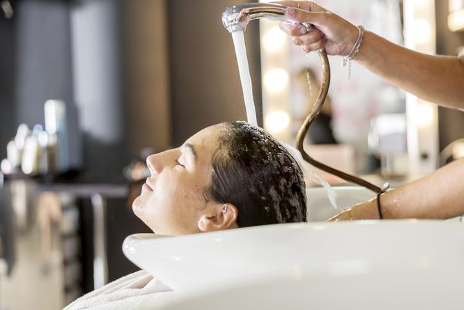 Relaxed female having her hair washed by stylist
